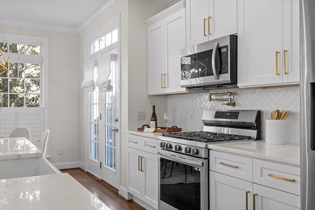 kitchen featuring white cabinets, light stone counters, tasteful backsplash, plenty of natural light, and appliances with stainless steel finishes