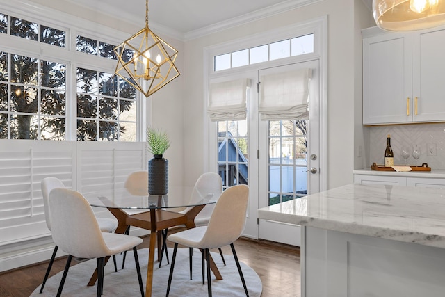 dining space with an inviting chandelier, ornamental molding, and dark hardwood / wood-style flooring