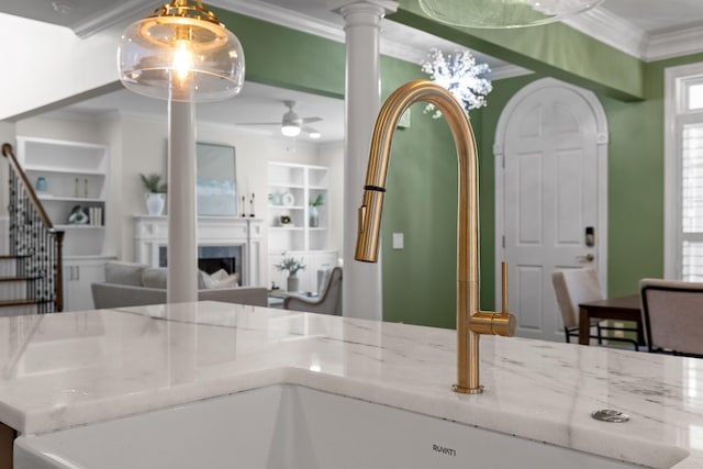 kitchen with ceiling fan, hanging light fixtures, light stone countertops, built in shelves, and crown molding