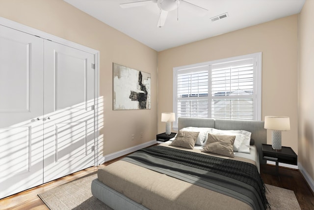 bedroom with ceiling fan, dark wood-type flooring, and a closet