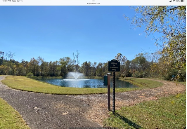 surrounding community with a water view and a lawn