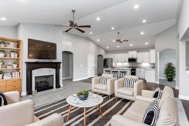 carpeted living room featuring a fireplace, high vaulted ceiling, ceiling fan, and sink