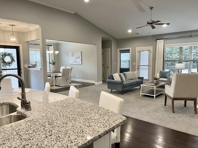 living room with sink, crown molding, dark hardwood / wood-style floors, ceiling fan with notable chandelier, and vaulted ceiling