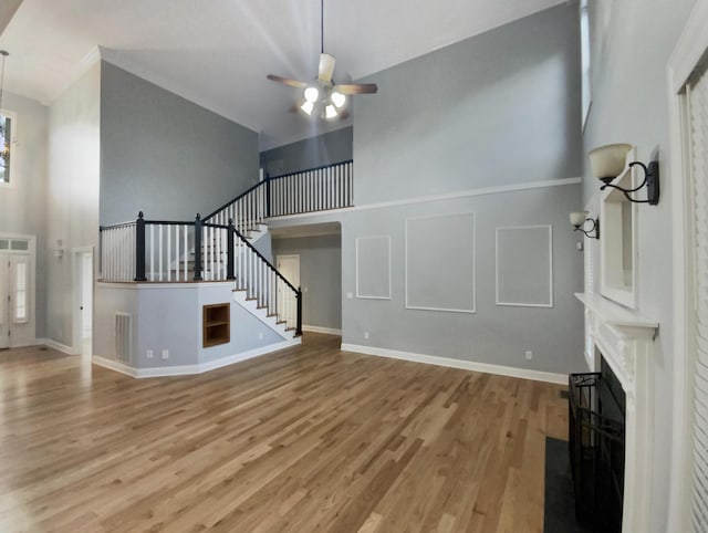 unfurnished living room featuring ceiling fan, a towering ceiling, and light hardwood / wood-style flooring