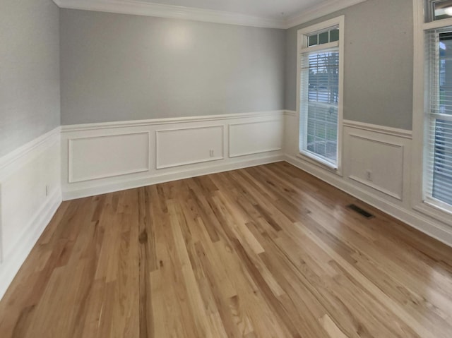 empty room featuring crown molding and light hardwood / wood-style flooring