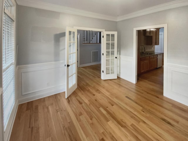 empty room with crown molding, french doors, light hardwood / wood-style flooring, and sink