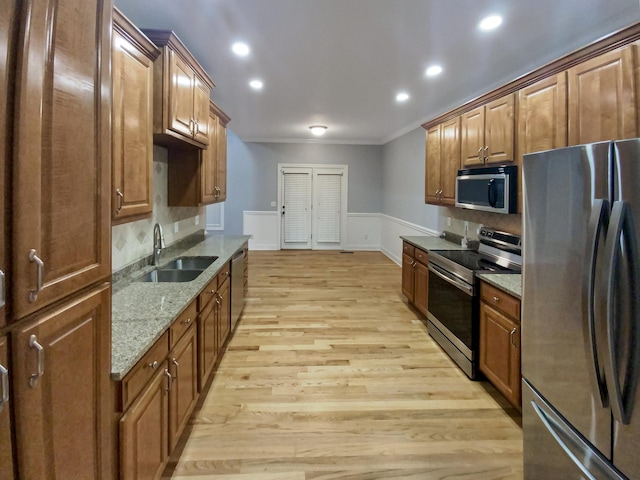 kitchen featuring light stone countertops, appliances with stainless steel finishes, tasteful backsplash, sink, and light hardwood / wood-style flooring