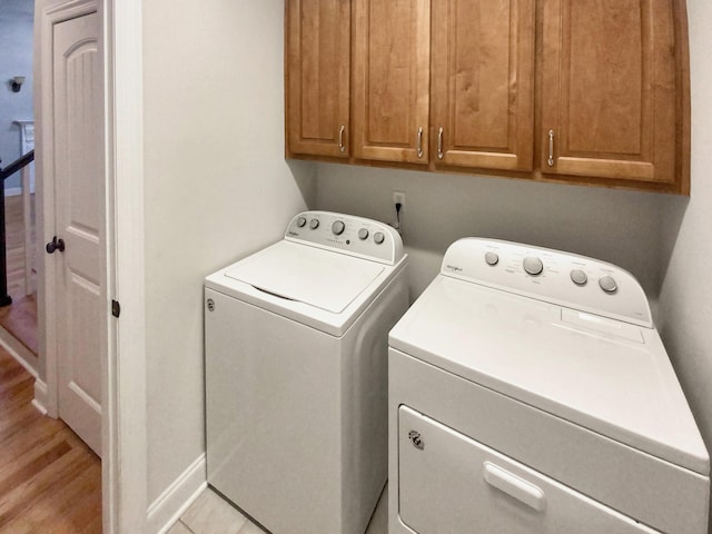 laundry area featuring washer and clothes dryer, cabinets, and light hardwood / wood-style floors