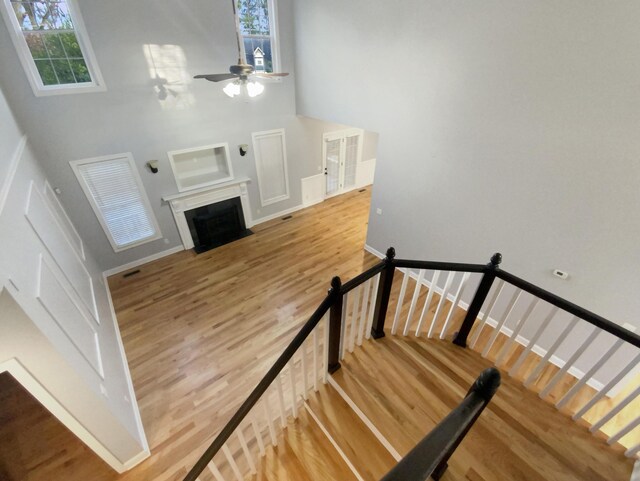 stairway featuring ceiling fan, wood-type flooring, and a towering ceiling