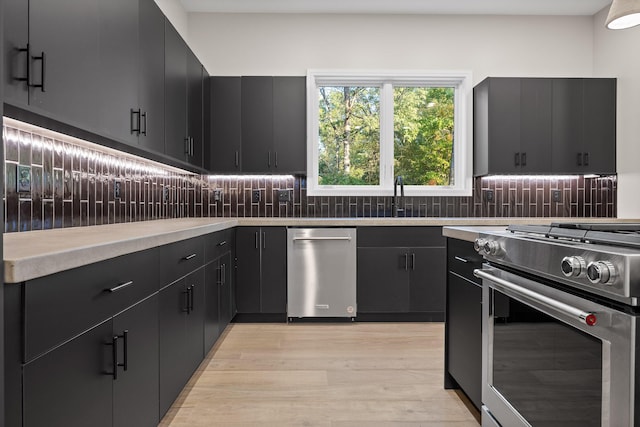 kitchen with sink, light wood-type flooring, decorative backsplash, and high end stainless steel range