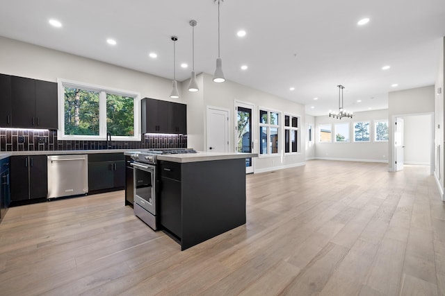 kitchen featuring stainless steel appliances, decorative light fixtures, a center island, and light wood-type flooring