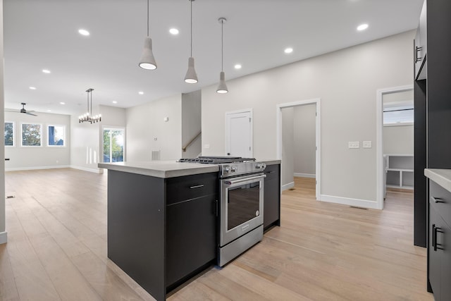 kitchen featuring decorative light fixtures, a center island, light wood-type flooring, ceiling fan with notable chandelier, and gas range