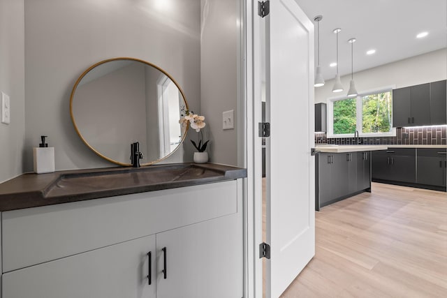 bathroom featuring hardwood / wood-style floors, vanity, and decorative backsplash