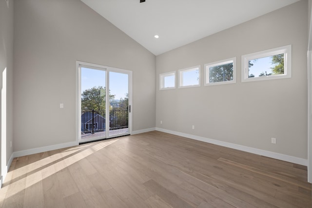 empty room featuring high vaulted ceiling and light wood-type flooring