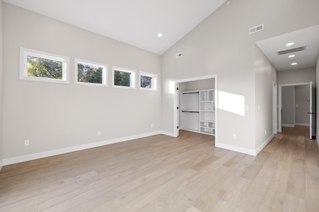 unfurnished room featuring high vaulted ceiling and light hardwood / wood-style flooring