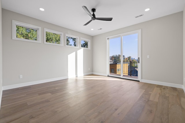 unfurnished room featuring ceiling fan, hardwood / wood-style flooring, and a healthy amount of sunlight