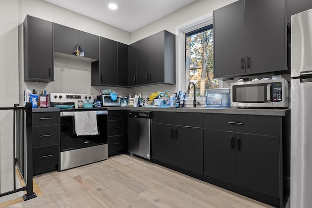 kitchen with appliances with stainless steel finishes, light hardwood / wood-style flooring, and sink