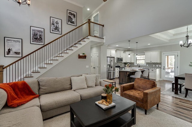 living room featuring light wood-type flooring, crown molding, a chandelier, and sink