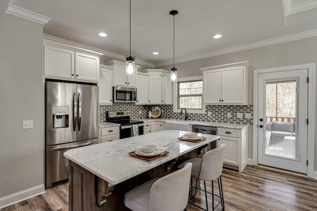 kitchen with appliances with stainless steel finishes, hanging light fixtures, a center island, dark hardwood / wood-style flooring, and white cabinetry