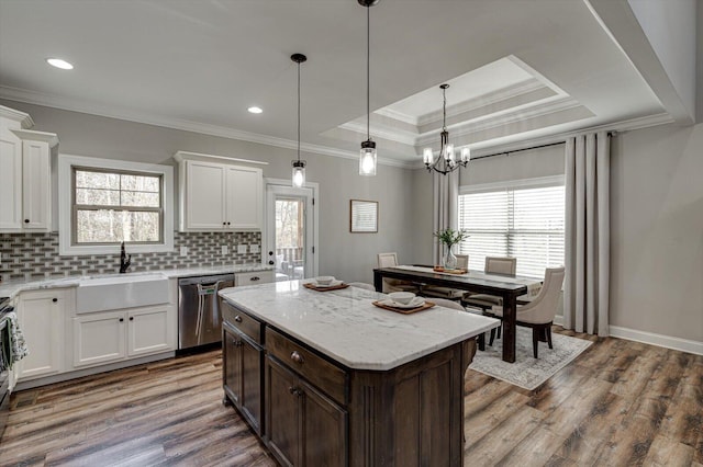 kitchen with stainless steel appliances, a kitchen island, white cabinets, and a tray ceiling