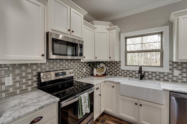 kitchen featuring light stone counters, stainless steel appliances, backsplash, white cabinetry, and sink