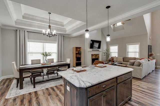 kitchen with hanging light fixtures, a raised ceiling, a brick fireplace, dark hardwood / wood-style flooring, and dark brown cabinetry