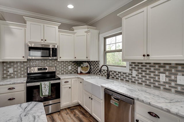 kitchen with stainless steel appliances, white cabinets, sink, and backsplash