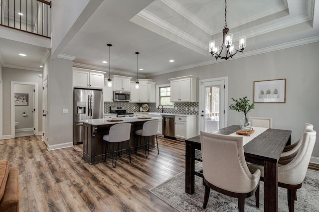 dining space with hardwood / wood-style flooring, a notable chandelier, crown molding, and sink