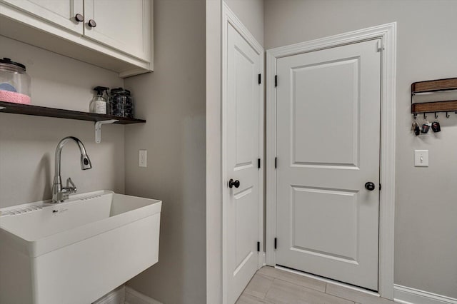 laundry area with sink, light tile patterned floors, and cabinets