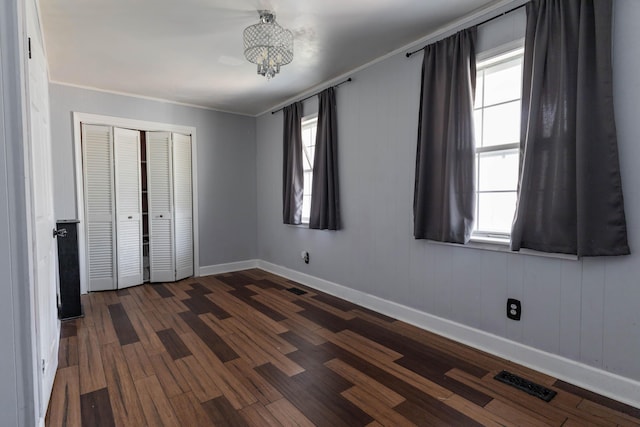 unfurnished bedroom featuring ornamental molding, dark hardwood / wood-style floors, and a closet