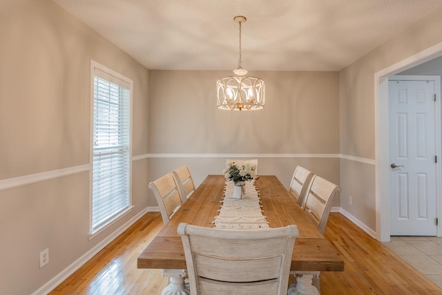 dining area with light hardwood / wood-style floors and an inviting chandelier