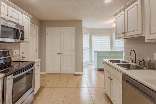 kitchen featuring appliances with stainless steel finishes, a textured ceiling, sink, and light tile patterned floors