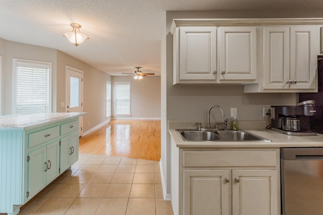 kitchen featuring light tile patterned floors, ceiling fan, sink, white cabinetry, and stainless steel dishwasher