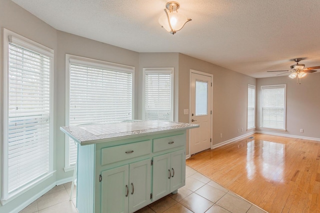 kitchen with light tile patterned flooring, a textured ceiling, a wealth of natural light, and green cabinets