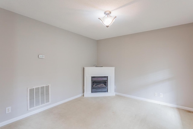 unfurnished living room featuring a textured ceiling and light colored carpet