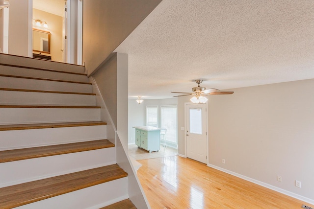 staircase with ceiling fan, a textured ceiling, and hardwood / wood-style flooring