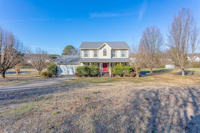 view of front of house featuring a porch, a front yard, and a garage