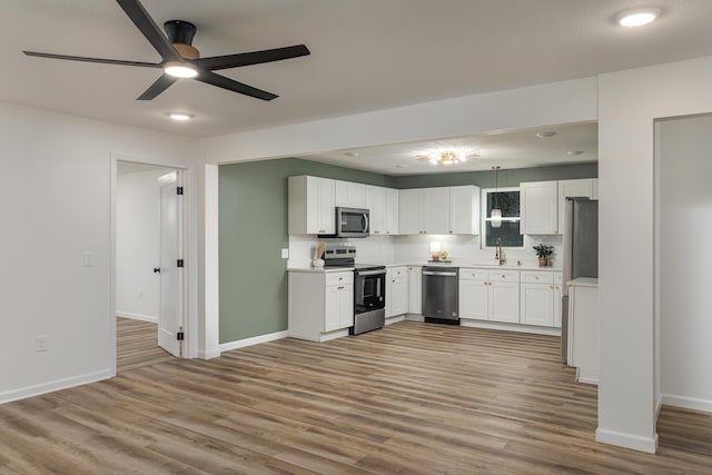 kitchen featuring appliances with stainless steel finishes, ceiling fan, sink, white cabinetry, and backsplash