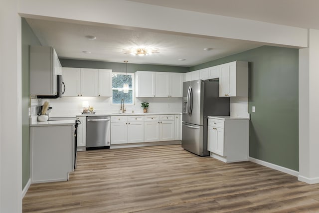 kitchen featuring white cabinets, backsplash, light hardwood / wood-style flooring, and appliances with stainless steel finishes