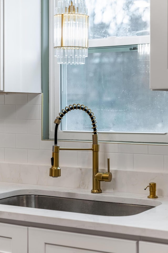 details with sink, white cabinetry, and backsplash