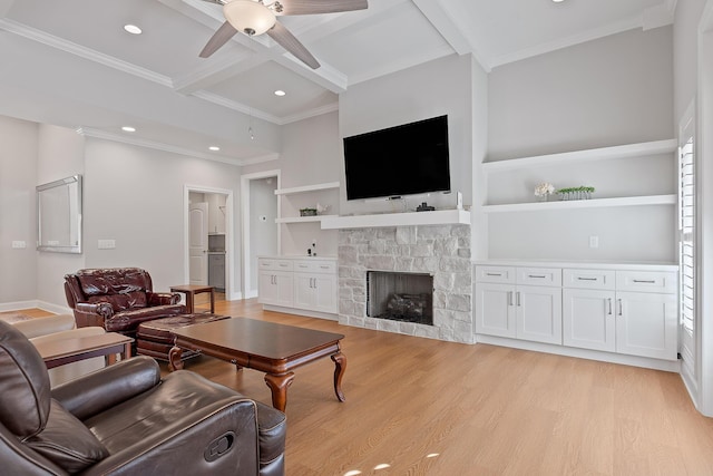 living area with baseboards, beamed ceiling, a stone fireplace, light wood-style flooring, and a ceiling fan