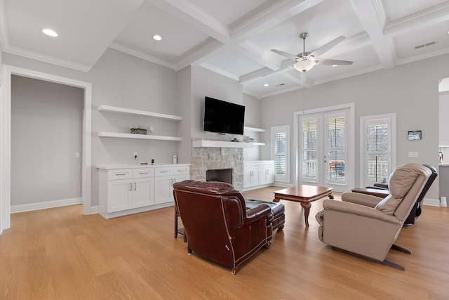 living room featuring ceiling fan, coffered ceiling, a fireplace, beamed ceiling, and light wood-type flooring