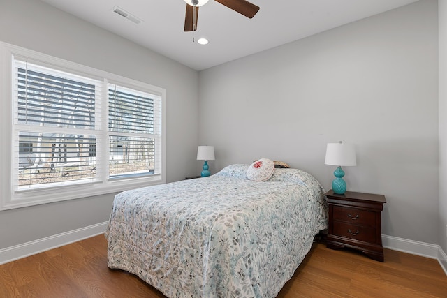 bedroom featuring visible vents, ceiling fan, baseboards, and wood finished floors