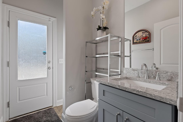 bathroom featuring vanity, toilet, and baseboards