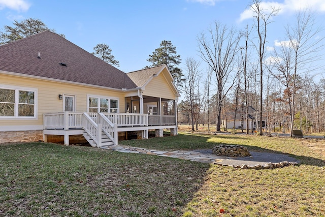 back of house with roof with shingles, a lawn, a sunroom, and an outdoor fire pit