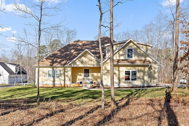 view of front of home with a front yard and a shingled roof