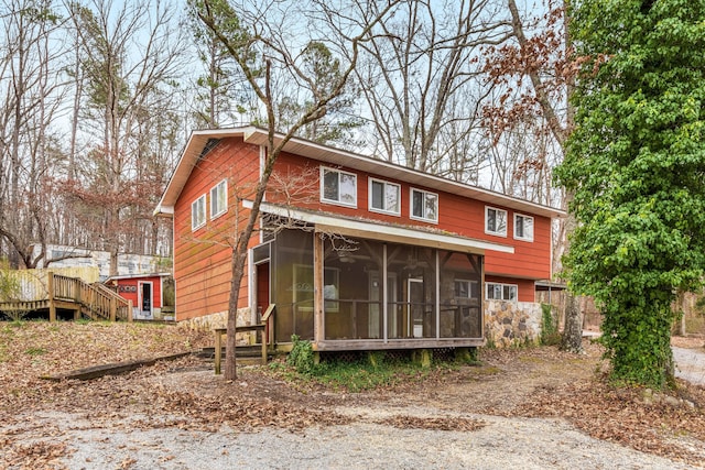 back of property with ceiling fan and a sunroom