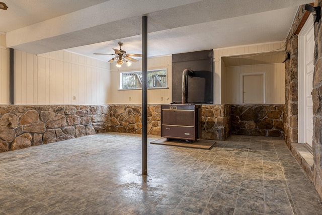 basement featuring ceiling fan, a textured ceiling, and wooden walls