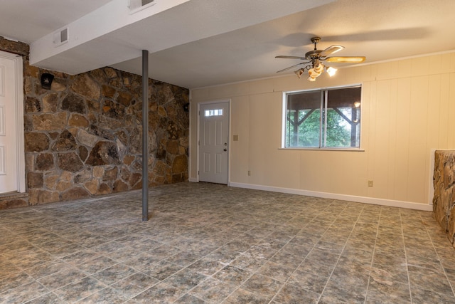 basement with ceiling fan and wooden walls