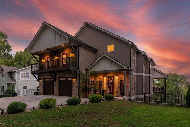 view of front of property with a balcony, a yard, and a garage